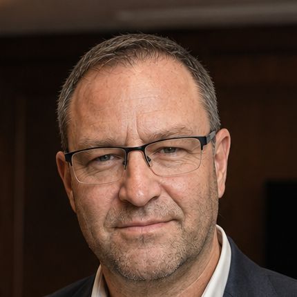 Forrest Andrew Jones, a man with short grey hair and half rim glasses, in a dark jacket and white shirt.